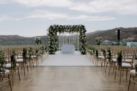 On an early summer weekend in May, guests gathered at the sunset terrace of the Royal Myconian hotel overlooking the Aegean Sea for the couple’s wedding ceremony. There, underneath a chuppah made of a mixture of white roses, peonies, olive branches, and greenery. After their first kiss, friends and family threw olive branch leaves.