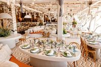 The Paraga beachfront ceremony took place under the most massive chuppah you’ve ever seen festooned with plush boho details, colorful summer blooms, berber blankets, throws and cushions, all glittering under the sun...