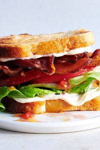 NYT Cooking: The success of a BLT hangs in its balance of salt, acid, lusciousness and crunch. This version is perfect, with a generous swipe of mayonnaise on each slice of toast, followed by a drizzle of olive oil, tomatoes marinated in red wine vinegar and salt, butter lettuce leaves and thick-cut bacon. Squash this closed and eat while the bacon is still warm. BLTs are often associated with summer, but t...