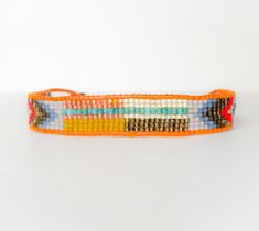 an orange and blue beaded bracelet sitting on top of a white table