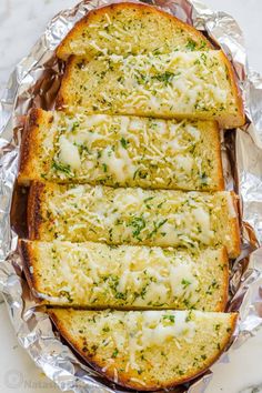 four slices of garlic bread on foil with parmesan sprinkles and melted cheese