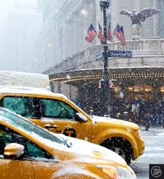 yellow taxi cabs parked in front of a building on a snowy day with american flags