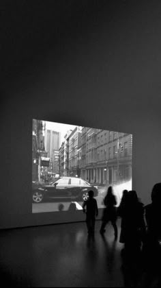 black and white photograph of people walking in an art gallery