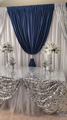 the table is set up with silver sequins and white flowers in vases