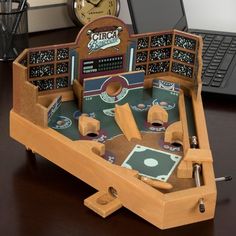 a wooden table top game set up on a desk with a laptop and clock in the background