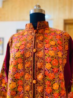 Embroidered Coat , Kashmiri Jacket Description Allow yourself to be lost in the lush flora of Kashmir's enchanted forests every time you wear the Long Kashmiri Jacket. This Kashmiri embroidered jacket is crafted in 100% pure wool/ Pure Raw Silk and . This festival season, you'll be warmed by not just the luxurious fabric but also by our artisans' love for their craft. ● 100% Pure wool / Pure raw Silk ● Crafted in Kashmir ● Traditionally embroidered by our artisans ● Can Also Be Customised In col Traditional Nehru Jacket With Floral Print, Fall Outerwear With Multicolor Embroidery And Floral Print, Fall Floral Print Outerwear With Multicolor Embroidery, Fall Floral Print Multicolor Embroidered Outerwear, Fall Multicolor Embroidered Floral Outerwear, Winter Outerwear With Floral Embroidery And Stand Collar, Multicolor Embroidered Outerwear With Stand Collar For Fall, Spring Outerwear With Resham Embroidery, Traditional Floral Print Outerwear For Spring