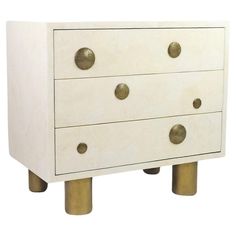 a white and gold chest of drawers with four brass knobs on each drawer,