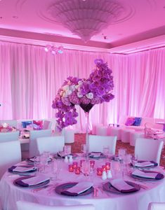 the table is set with purple flowers and place settings