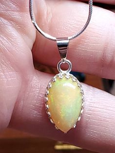 "4.00 carat green, yellow and orange natural Ethiopian opal in a Lacey bezel silver setting on a silver 18 inch chain. 5/8\" x 7/16 is the size of the stone,I will make a chain any length you like." Opal Gemstone Round Pendant Necklace, White Gold Opal Round Necklace, Opal Cabochon Round Pendant Necklace, Opal Gemstone Round Pendant Jewelry, Opal Cabochon Round Pendant Necklaces, Opal Gemstone Pendant Jewelry, Sterling Silver Cabochon Teardrop Pendant Necklace, Sterling Silver Teardrop Cabochon Necklace, Fine Jewelry Opal Cabochon Necklace