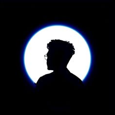 the silhouette of a man with glasses in front of a full moon, taken at night