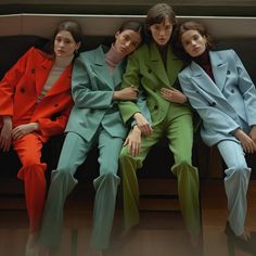 three models in colorful suits sitting on a bench