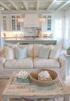 a living room filled with white furniture and lots of pillows on top of it's couch