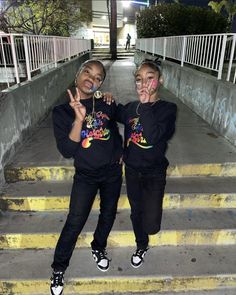 two young women standing on steps with their hands in the air and making peace signs