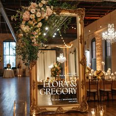 an ornate gold framed mirror with flowers and greenery on the front is surrounded by candles