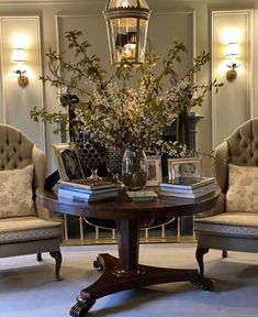 a living room with two chairs and a table filled with books on top of it