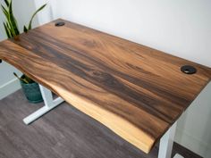 a wooden desk with two metal legs and a potted plant on the other side