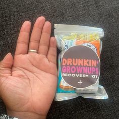 a person holding their hand up in front of a bag of gummy bears with the words drunk grown recovery kit on it