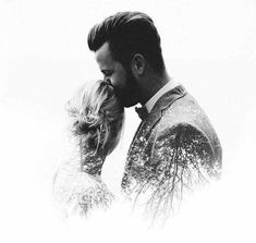 a black and white photo of a man and woman kissing each other in the snow