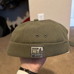 Never Worn Green Brimless Hat. Casual Flat Cap For Summer, Casual Summer Flat Cap, Casual Adjustable Brimmed Beanie, Trendy Khaki Cotton Hat, Urban Short Brim Hat, One Size Fits Most, Urban Hat With Short Brim, One Size Fits Most, Urban Short Brim Hat One Size, Casual Solid Brimmed Baseball Cap, Urban Short Brim Hat