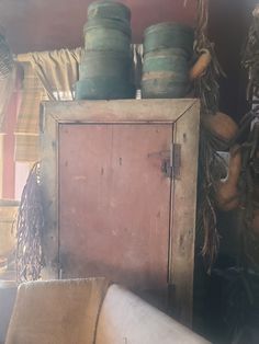 an old wooden cabinet with many pots on top