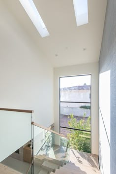 an empty staircase with glass railings leading up to the second floor and skylights above