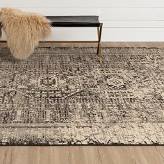 an area rug with a bench in the middle and a fur pillow on top of it