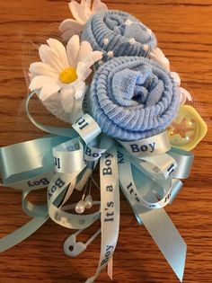 a blue flower with white flowers on top of it sitting on a wooden table next to ribbon