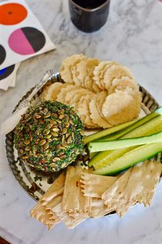 a plate with crackers, cucumbers and other food on it