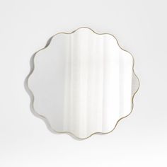 a white wall mirror with gold trim around the edge and an oval shaped frame on top