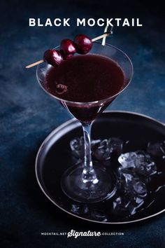 the black cocktail is garnished with cherries