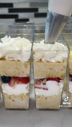 three desserts in plastic containers with white frosting and strawberries on the top