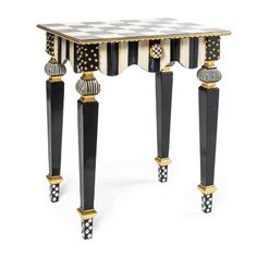 a black and white checkered table with gold trimmings on the legs, topped by