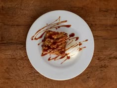 a white plate topped with food covered in sauce and ice cream on top of a wooden table