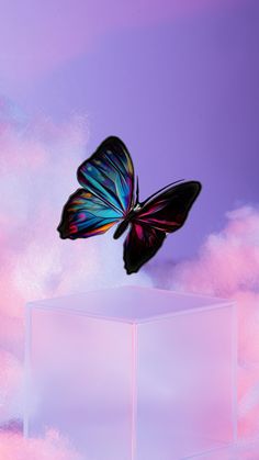 a butterfly flying over a white cube in the sky with pink and blue clouds behind it