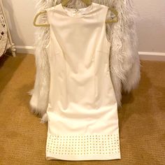 a white dress on a hanger in front of a wall with a fur coat over it