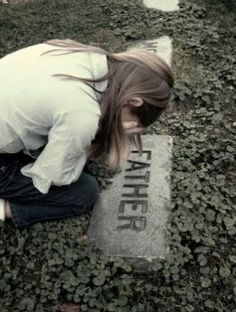 a woman kneeling down next to a grave with the word father written on it in black and white