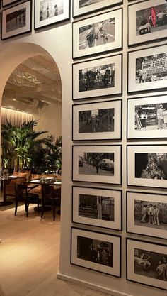 a wall full of black and white photos in an office building with arches leading into the dining room