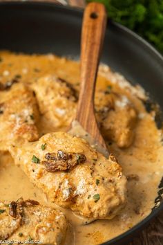 some meatballs and gravy in a skillet with a wooden spatula