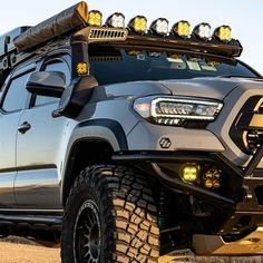 the front end of a silver truck with lights on it's bumper and four wheel drive