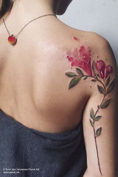 the back of a woman's shoulder with flowers painted on her arm and chest