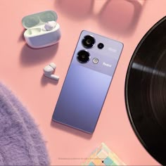 an iphone, headphones and record player on a pink surface next to a vinyl album