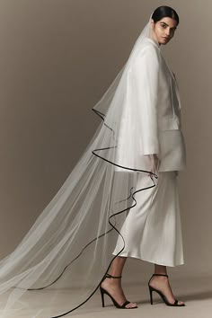 a woman in a white dress with a long veil on her head and black heels