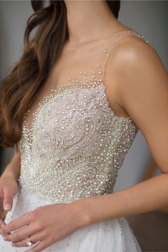 a woman wearing a wedding dress with beading on it