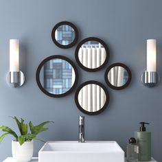 modern bathroom with round mirrors on the wall and white sink in front of grey walls