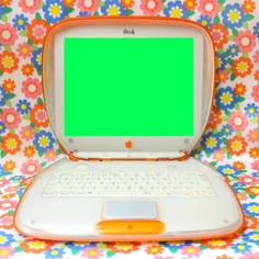 an open laptop computer sitting on top of a colorful flowered cloth covered tablecloth