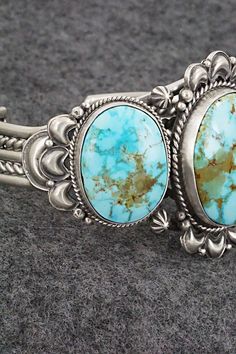 This stunning Kingman turquoise and sterling silver bracelet was made by Navajo silversmith Derrick Gordon. The back is signed Derrick and stamped Sterling.Size: 5 1/2" (will fit up to a 6 3/8" wrist)Gap: 7/8"Length: 1 5/8"Free shipping on all orders! We ship with USPS and always include tracking. All orders ship within a day of payment.Returns are accepted up to 30 days after you receive your order. Just send us a message. Our shop offers cash back or store credit. The item must be returned in new condition. Western Style Blue Sterling Silver Collectible Bracelet, Western Turquoise Bracelet With Patina, Western Style Blue Sterling Silver Bracelet Collectible, Western Turquoise Bracelet With Concho, Western Turquoise Bracelets With Concho, Western Style Turquoise Bracelet With Concho, Turquoise Western Style Collectible Bracelets, Kingman Turquoise, Spring Sale