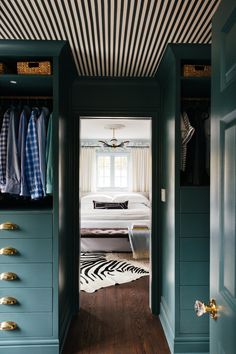 an open closet with clothes on hangers and drawers in the door, next to a bed