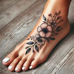 a woman's foot with flowers and leaves tattoo on it, sitting on a wooden floor