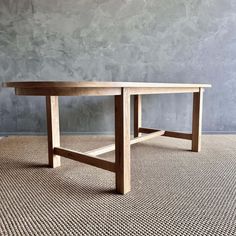 a wooden table sitting on top of a carpeted floor next to a gray wall