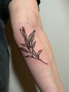 a black and white photo of a leaf tattoo on the arm